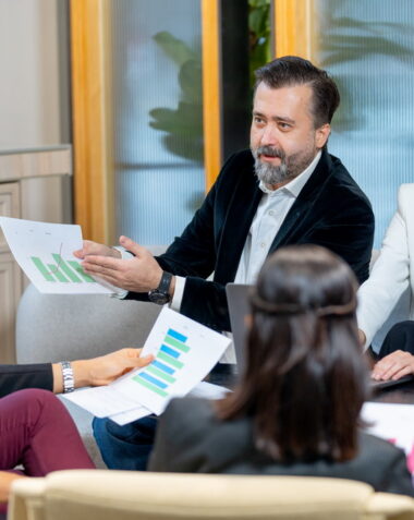 Asian business man discuss with Caucasian manager about the project in coworking space of the companee and join with other staffs.