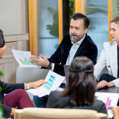 Asian business man discuss with Caucasian manager about the project in coworking space of the companee and join with other staffs.