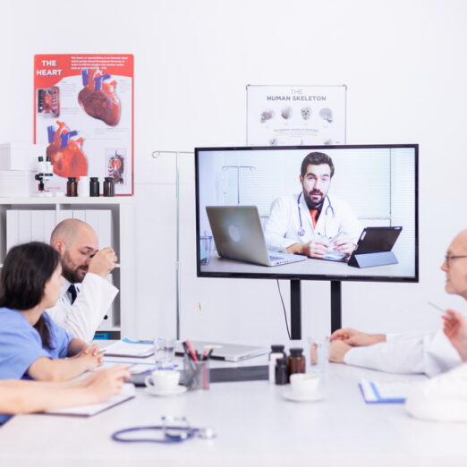 Medical staff talking with expert doctor during webinar in hospital conference room. Medicine staff using internet during online meeting with expert doctor for expertise.